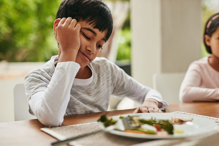 Boy looking unhappily at food on his plate