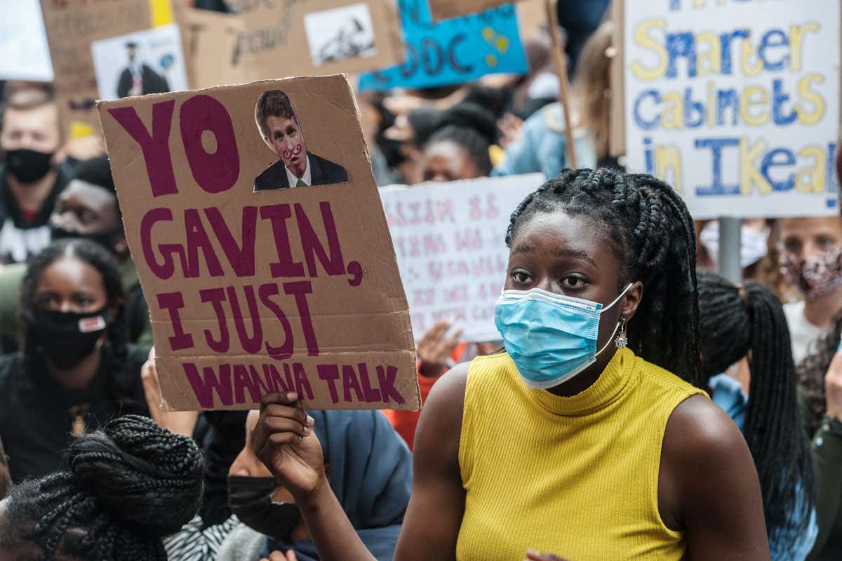 Protestor holds placard reading 'Yo Gavin, I just wanna talk'