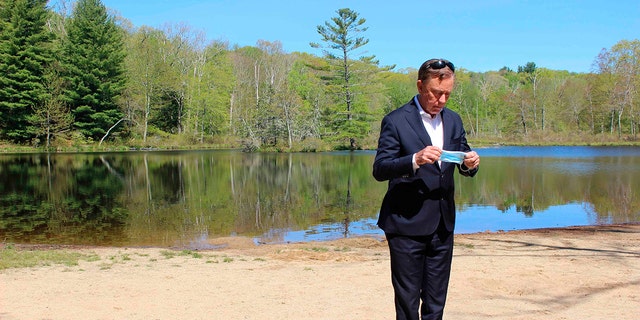 FILE - This photo from May 21, 2020, shows Connecticut Gov. Ned Lamont as he prepares to put on a face mask before his daily COVID-19 briefing, Gay City State Park in Hebron, Conn. Lamont's office say they will no longer provide daily updates on the number of people who have died in the state from COVID-19-related causes. (AP Photo/Pat Eaton-Robb, File)